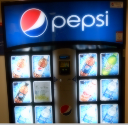 Pepsi specimen shows trademark use for soft drinks. The specimen is a photograph of a vending machine. The trademark is shown prominently at the top of the vending machine. 